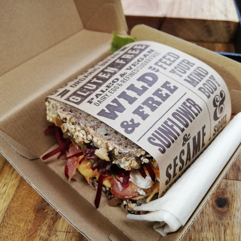 Fresh salad sandwich made with OMGoodness Sunflower & Sesame 'Wild & Free' GF Organic loaf of bread wrapped in product label which reads Gluten Free, Paleo & Vegan, Dairy, Egg & Refined Sugar Free